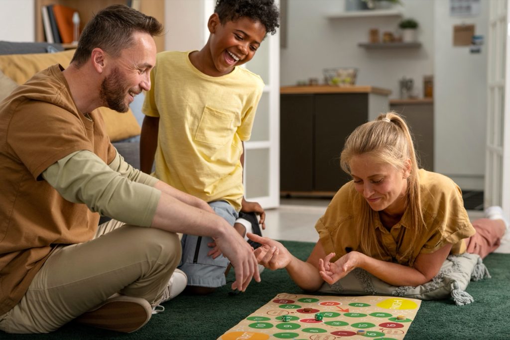 Familj med två barn spelar ett brädspel på vardagsrumsgolvet